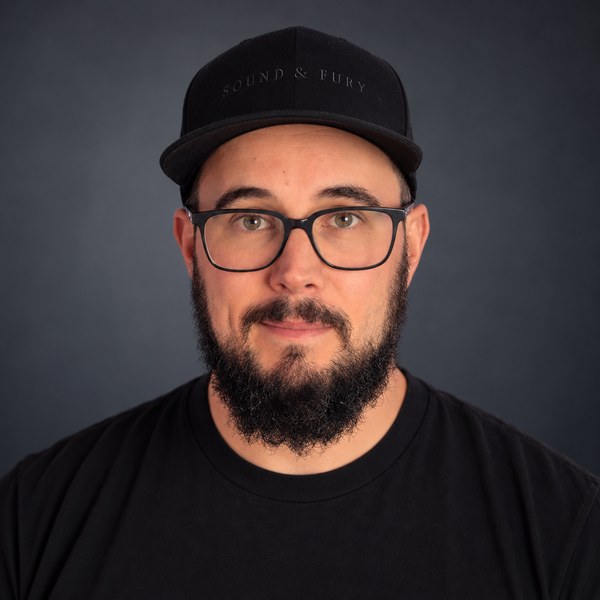 Matt Marcotte headshot, black cap and black tee on a grey backdrop